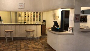 A bar area with stools, a counter, and a computer monitor. - Hotel Su Meriagu (Quartu Sant'Elena)