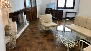 A living room with a glass coffee table, two sofas, a TV, and a fireplace. - Hotel Su Meriagu (Quartu Sant'Elena)