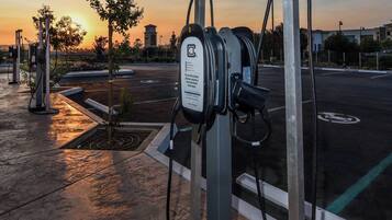 Eine Ladestation für Elektroautos mit einem Schild, umgeben von einem Parkplatz mit Sonnenuntergang.