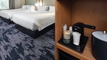 Une chambre d’hôtel avec deux lits, une machine à café et une tasse à café.