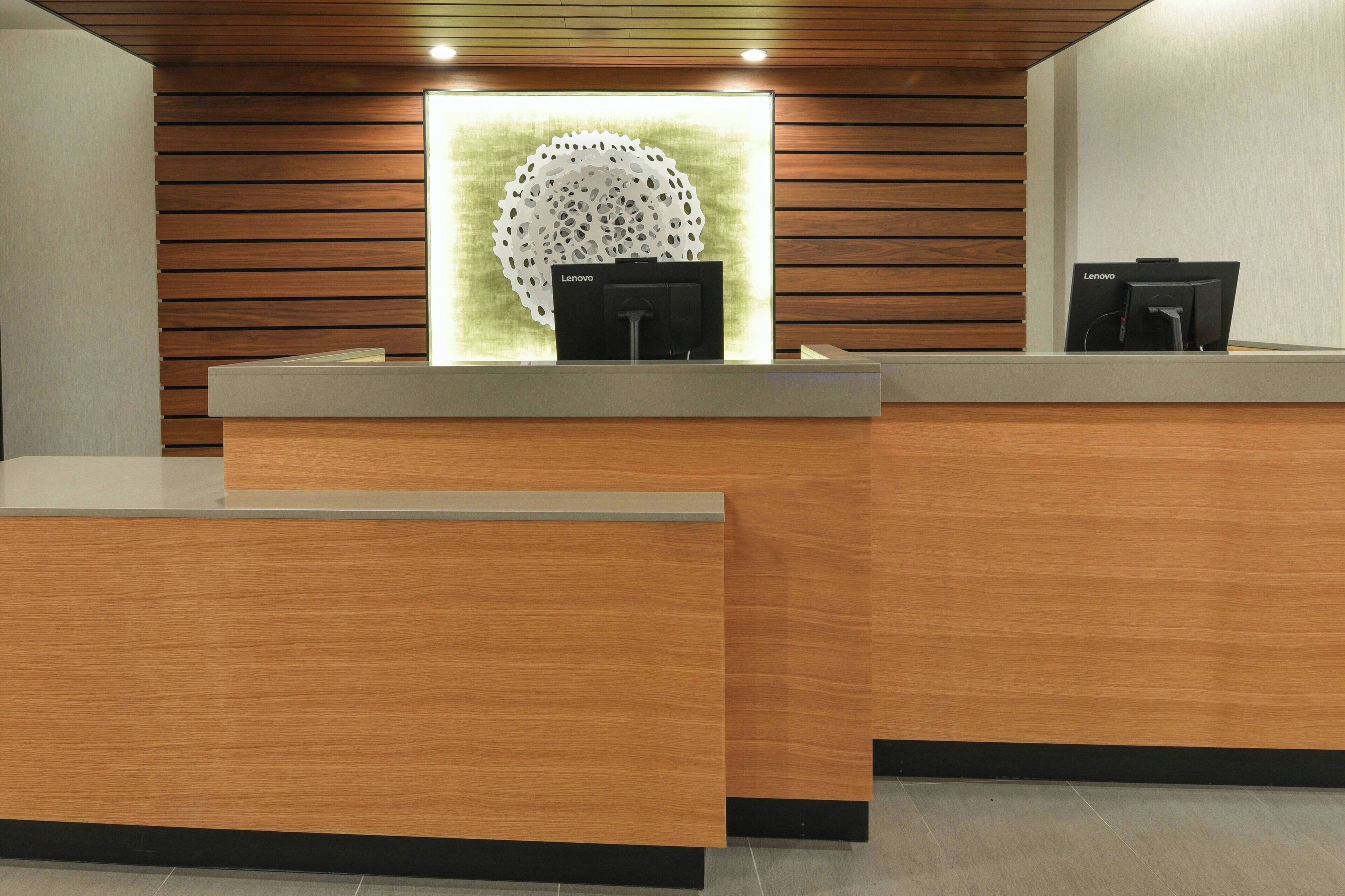 A reception desk with a modern design, featuring a wooden panel wall and a central decorative light fixture.