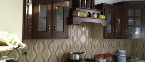 A kitchen with wooden cabinets, a gas stove, and various kitchen utensils.