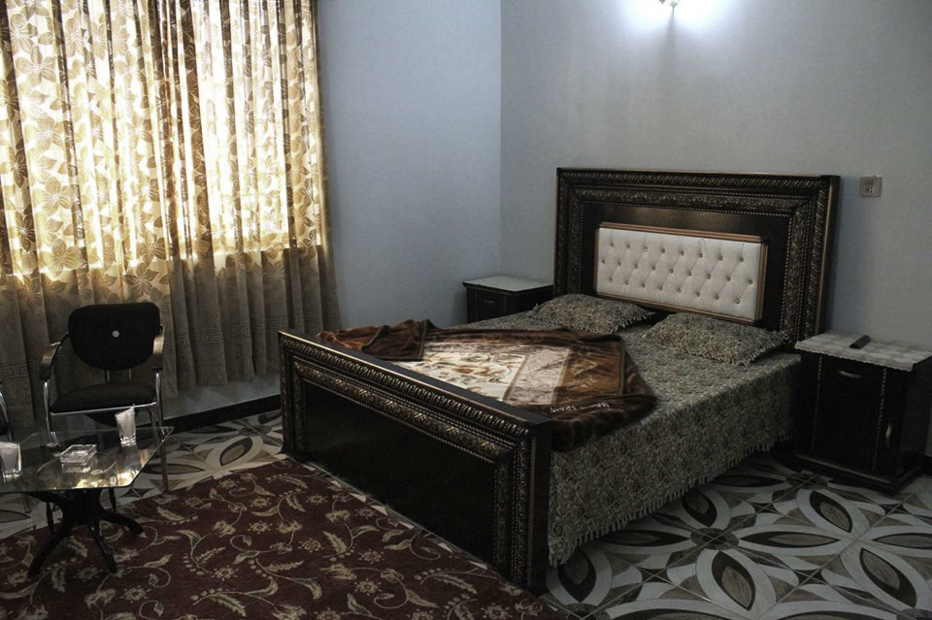 Une chambre à coucher avec un lit, une chaise, une petite table et une table de chevet.