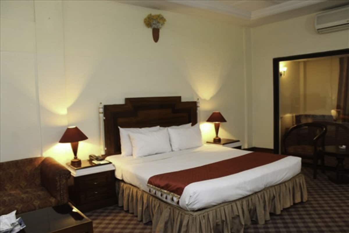 Ein Hotelzimmer mit einem großen Bett, zwei Nachttischen mit Lampen, einem Sessel und einem kleinen Tisch.