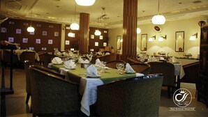 A restaurant with multiple tables set for dining, featuring a classic interior with chandeliers and framed pictures on the walls. - Sheza Inn Hotel Multan (Multan)