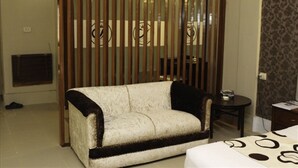 A room with a sofa, a small table, and a bed with a patterned bedspread. - Sheza Inn Hotel Multan (Multan)