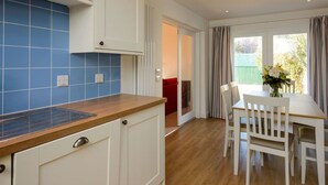 A modern kitchen with blue tiles, white cabinets, and a wooden countertop. - Glenconner Garden Cottage (North Berwick)