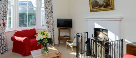 A living room with a red sofa, a TV, a fireplace, and a painting on the wall.