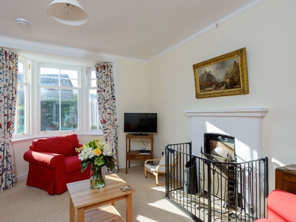 A living room with a red sofa, a TV, a fireplace, and a painting on the wall.