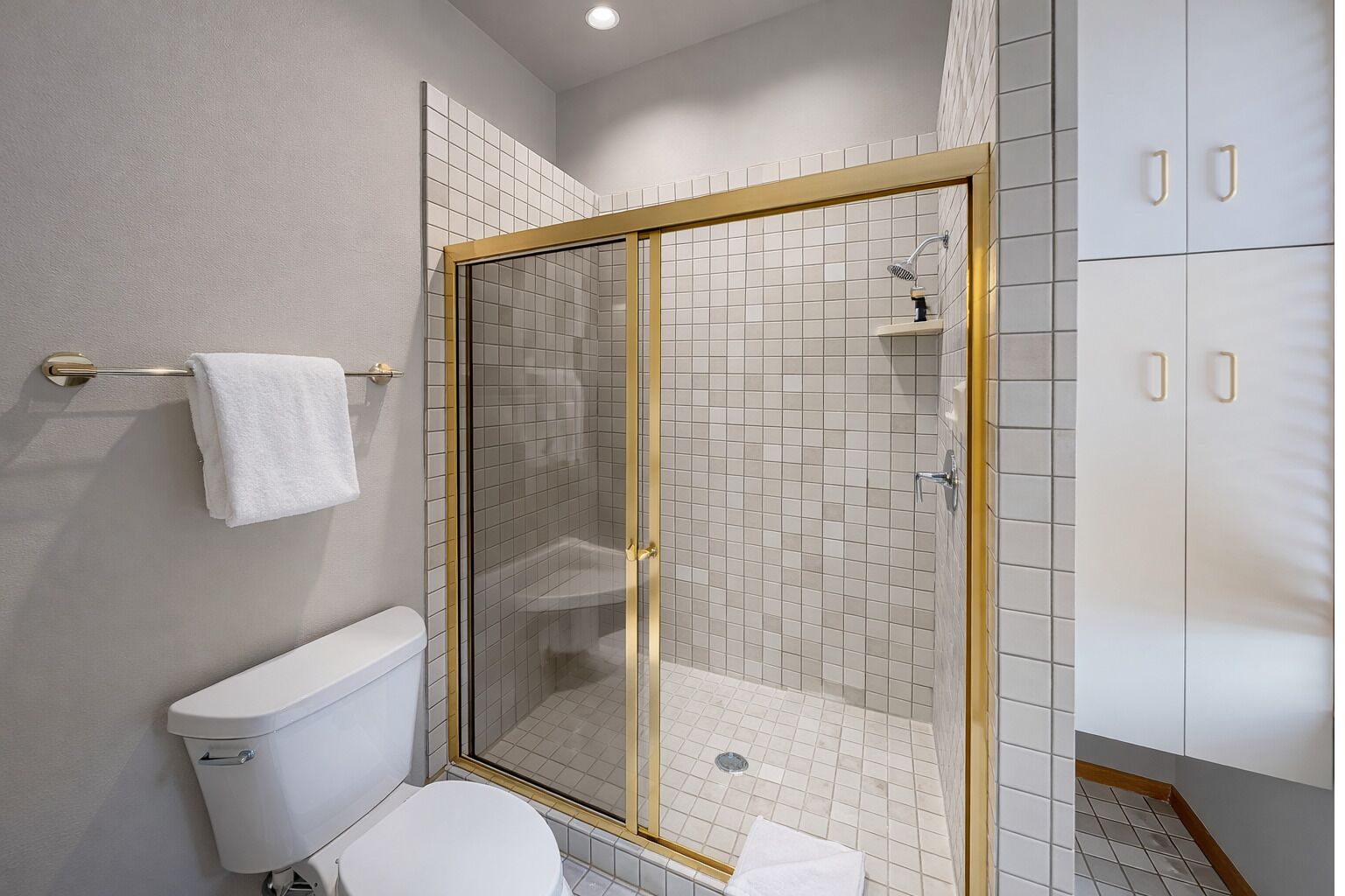 Modern top floor ensuite bathroom featuring a large walk-in shower with stylish gold trim and all necessary essentials for a refreshing stay.
