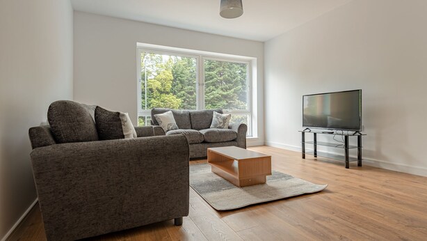 A modern living room with a sofa, a coffee table, and a TV. - Spacious Modern Apartment (Edinburgh)