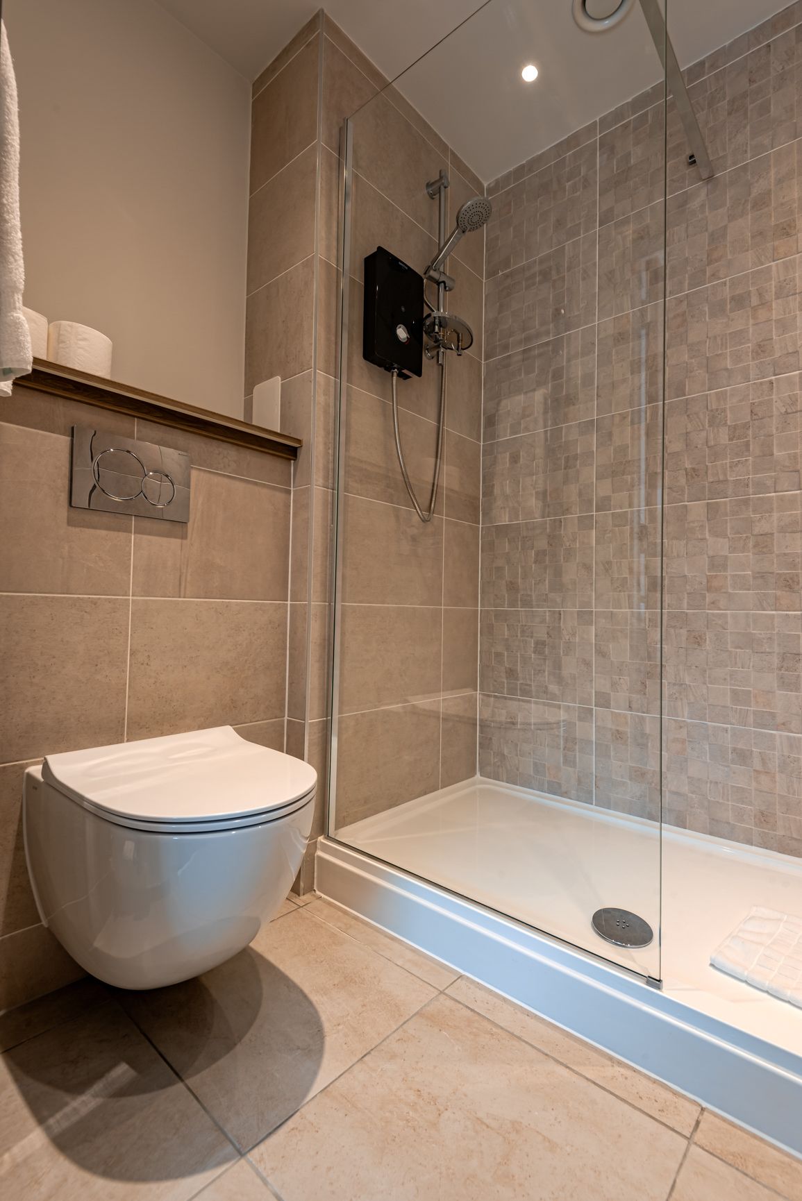 A modern bathroom with a glass-enclosed shower, a white toilet, and a tiled floor.