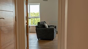 Un couloir menant à un salon équipé d’un canapé et d’un luminaire suspendu.