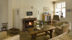 Ein gemütliches Wohnzimmer mit Kamin, bequemen Sitzmöglichkeiten und einem Bücherregal.