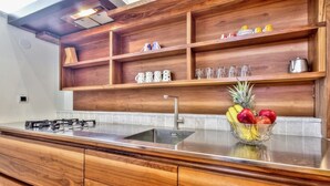 A kitchen with wooden cabinetry, a stainless steel countertop, a built-in sink, and a fruit bowl with apples and pineapples. - A one bedroom semibasement apartment - Lana 2 (Petrovija)