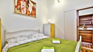 A bedroom with a bed, a wardrobe, a painting, and a shelf with items. - A one bedroom semibasement apartment - Lana 2 (Petrovija)