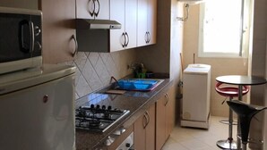 Une cuisine équipée d’une cuisinière à gaz, de placards, d’un réfrigérateur, d’un évier et d’une fenêtre.