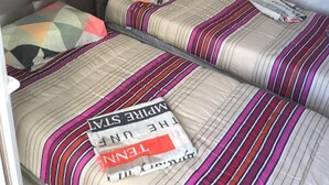Une chambre double avec deux lits, chacun étant équipé de draps à rayures et d’un oreiller.