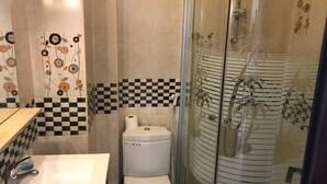 Une salle de bain avec des toilettes, un lavabo et une douche.