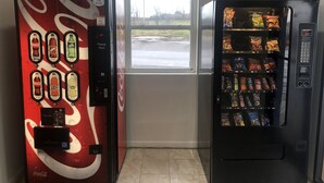 Two vending machines, one with Coca-Cola branded drinks and the other with snacks. - Troy Inn and Suites (Troy)