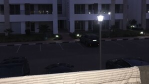 Un immeuble à plusieurs étages avec un parking situé devant.