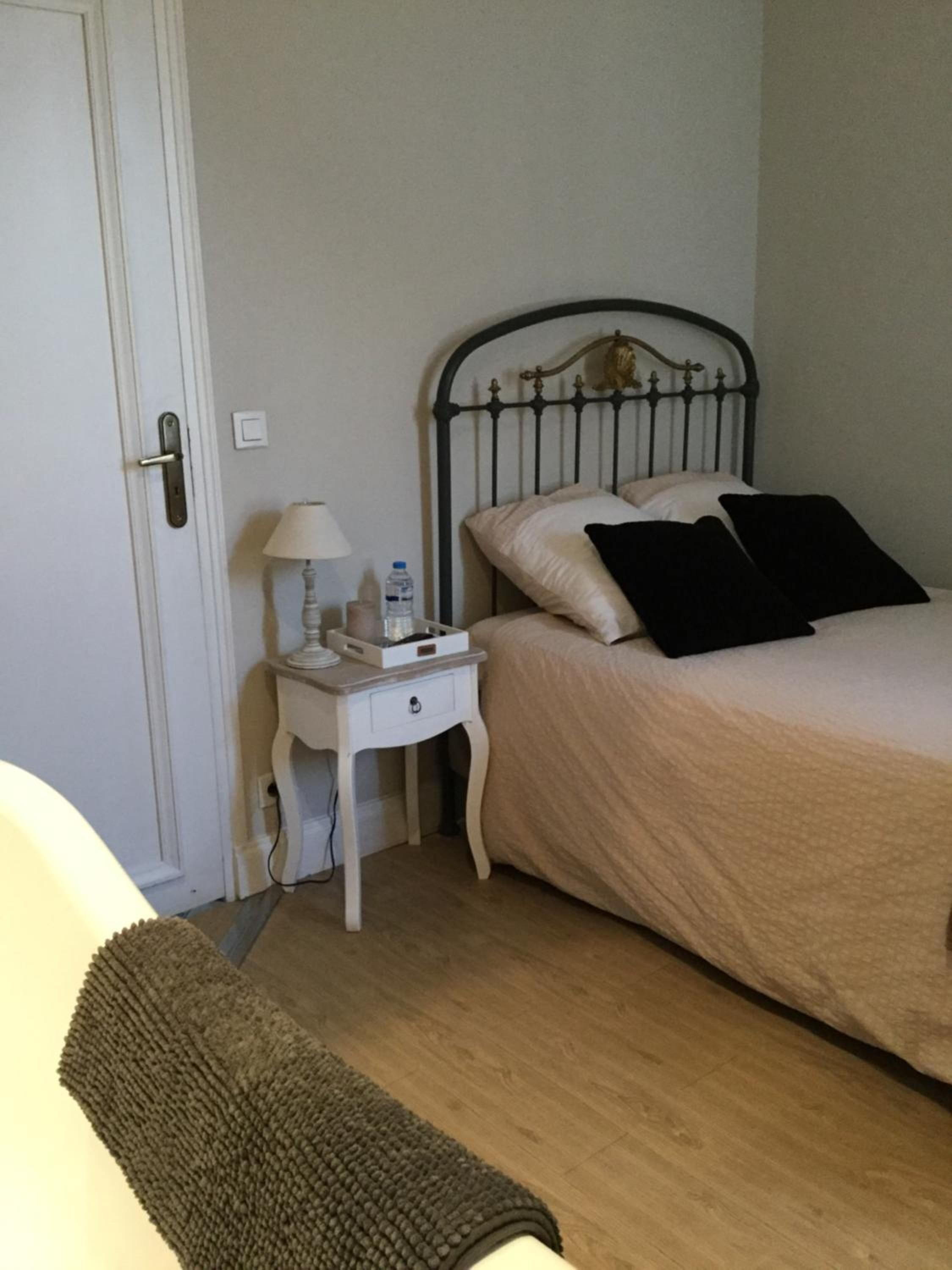 Une chambre à coucher avec un lit, une table de chevet, une lampe et une porte.