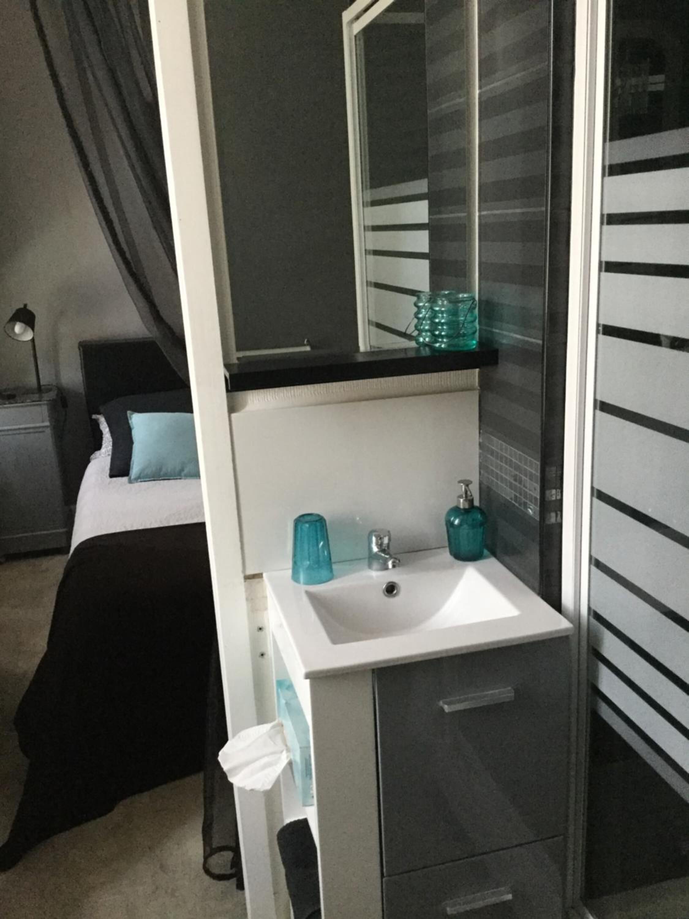 Un dormitorio con cama, mesita de noche, tocador, espejo, lavabo y armario.