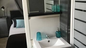 Un dormitorio con cama, mesita de noche, tocador, espejo, lavabo y armario.