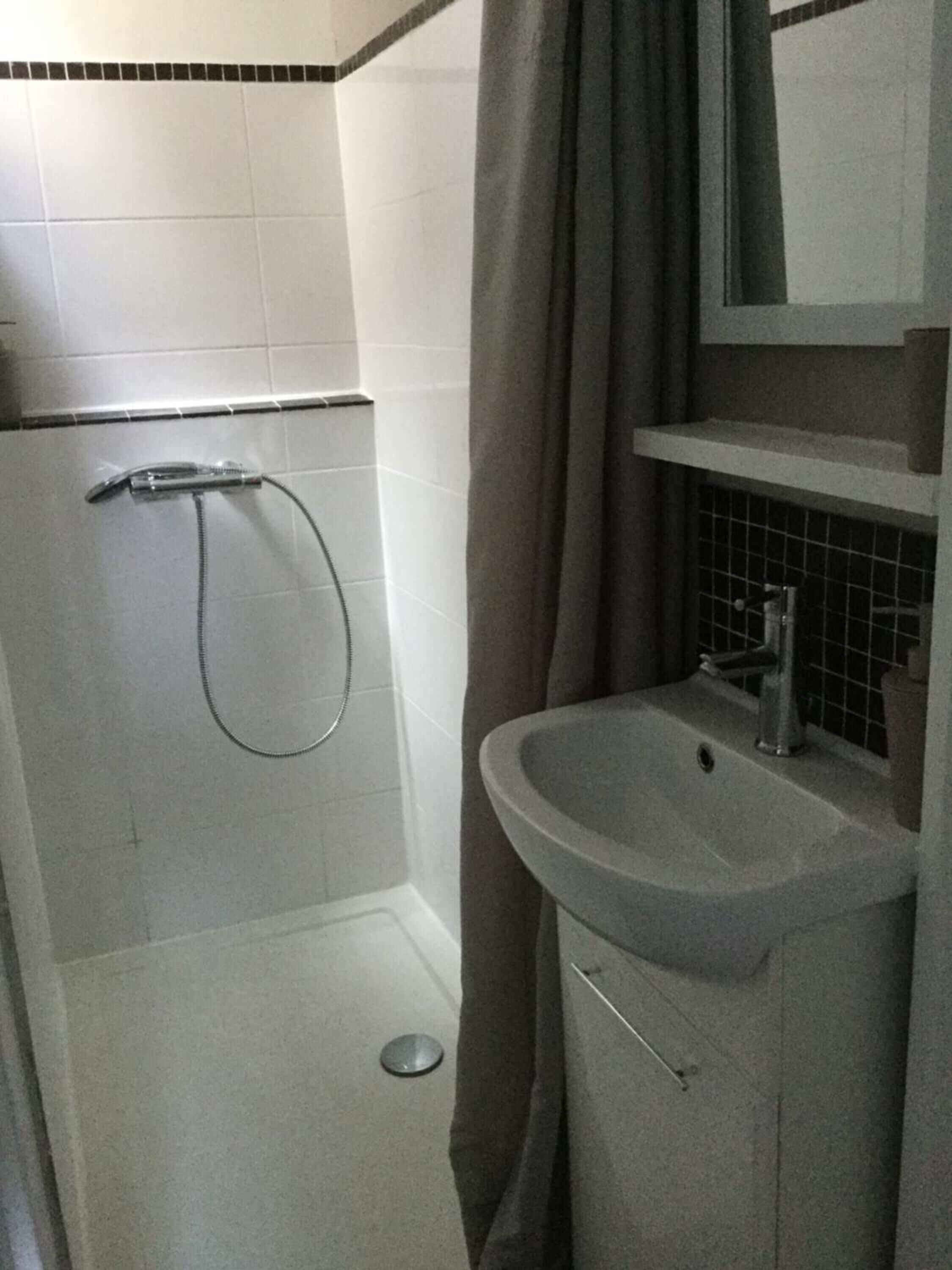 A small bathroom with a shower, a sink, and a mirror.