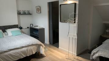 Une chambre à coucher avec deux lits, une table de chevet, une armoire, un miroir et une étagère ornée d’objets décoratifs.