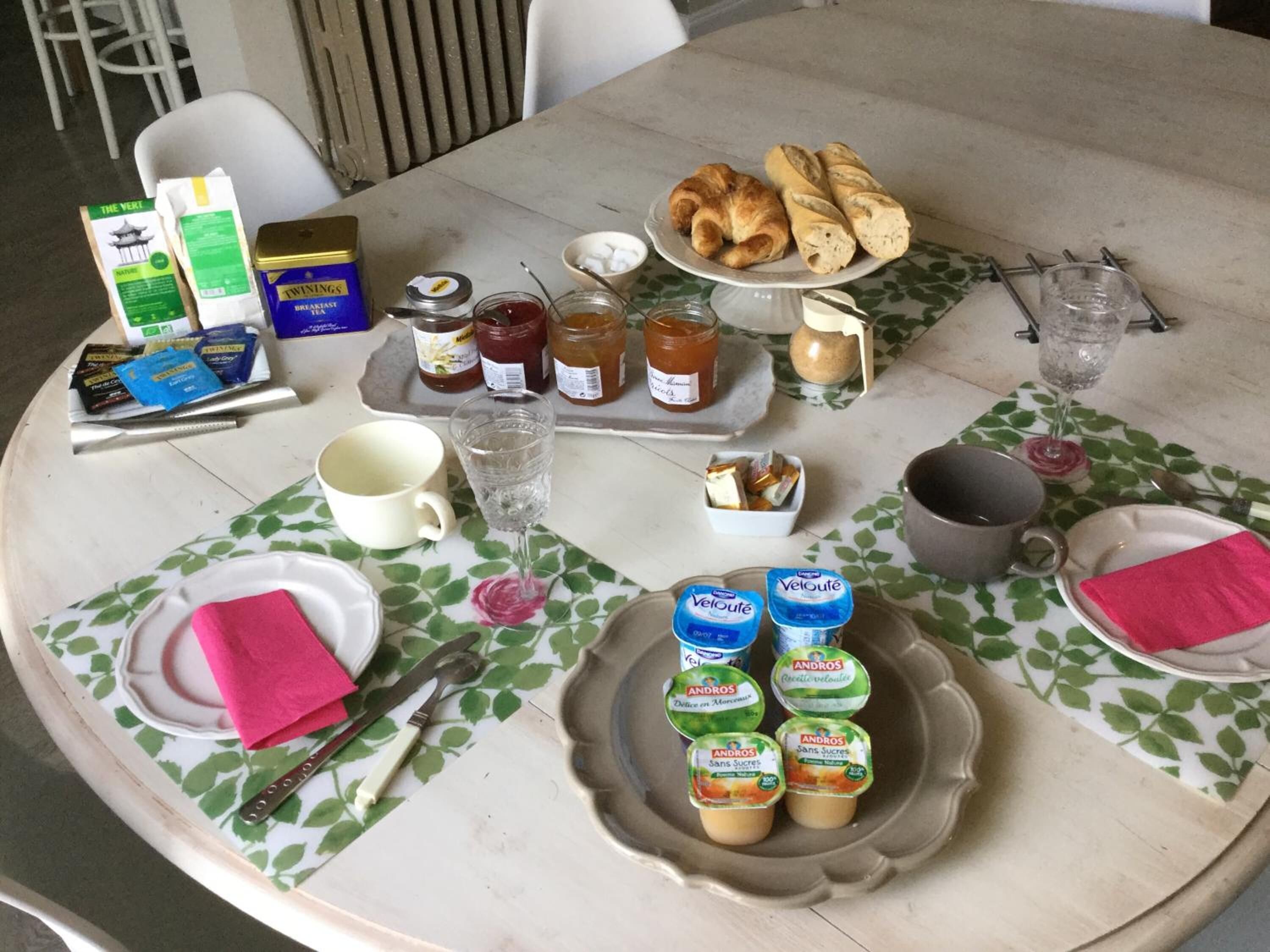 A breakfast table with croissants, jams, and yogurt.