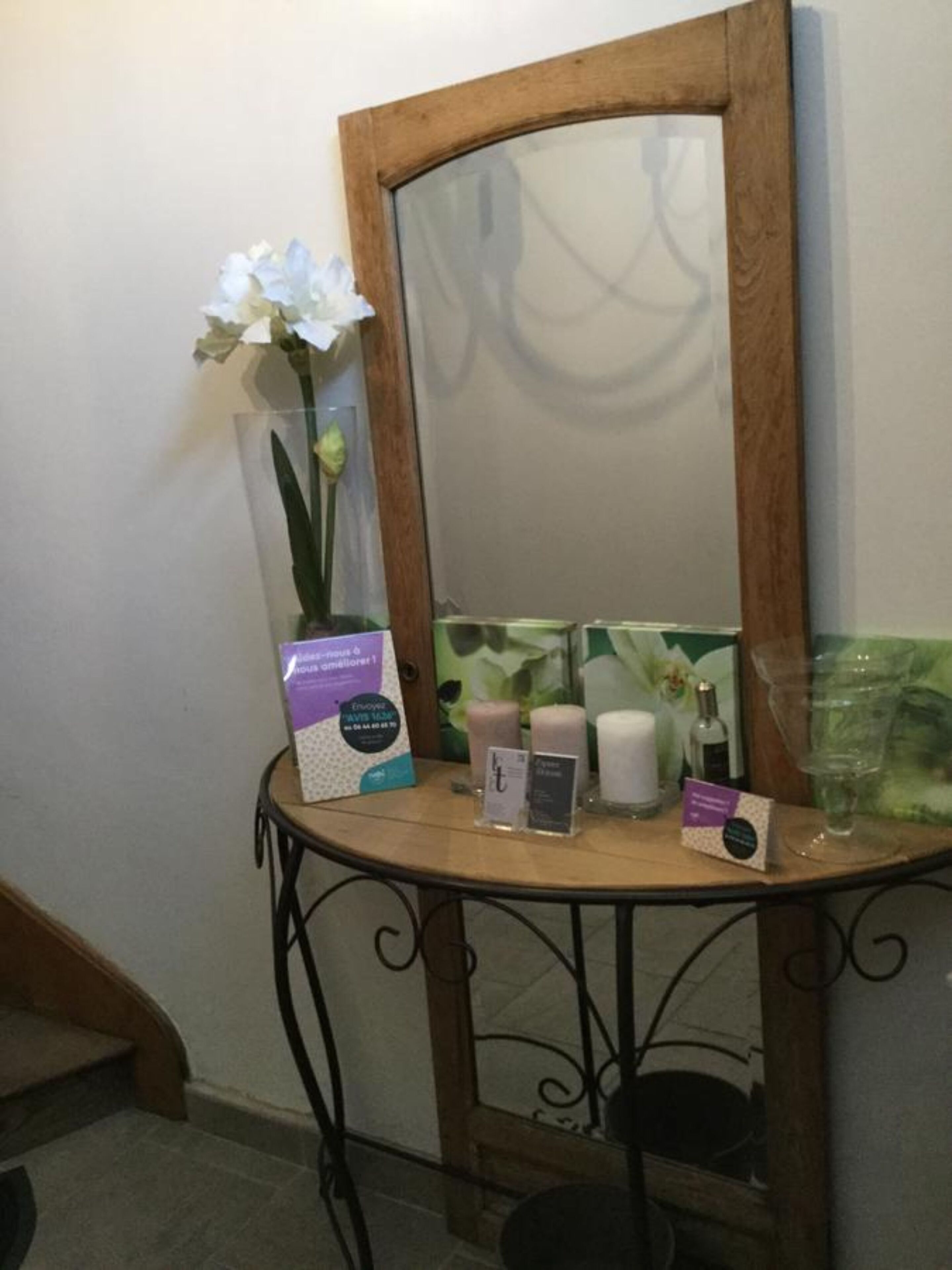 A small table with a mirror, a vase with an orchid, and various toiletries.