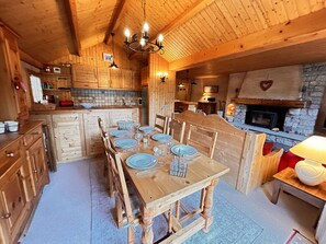 A wooden interior with a dining table set for six, a stone fireplace, and wooden cabinetry. - Spacious 4-Room Apartment for 6-8 in Méribel, Ski-In/Ski-Out, Fireplace, Pool, Near Shops (Méribel)