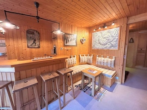 En mysig stuga med träpanel, en bar, sittplatser och konstverk på väggarna.