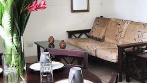 Uma área de jantar com uma mesa posta para dois, um sofá e um espelho na parede.