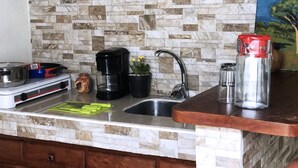 Cozinha com painel de parede de pedra, cafeteira, chaleira e saleiro no balcão.