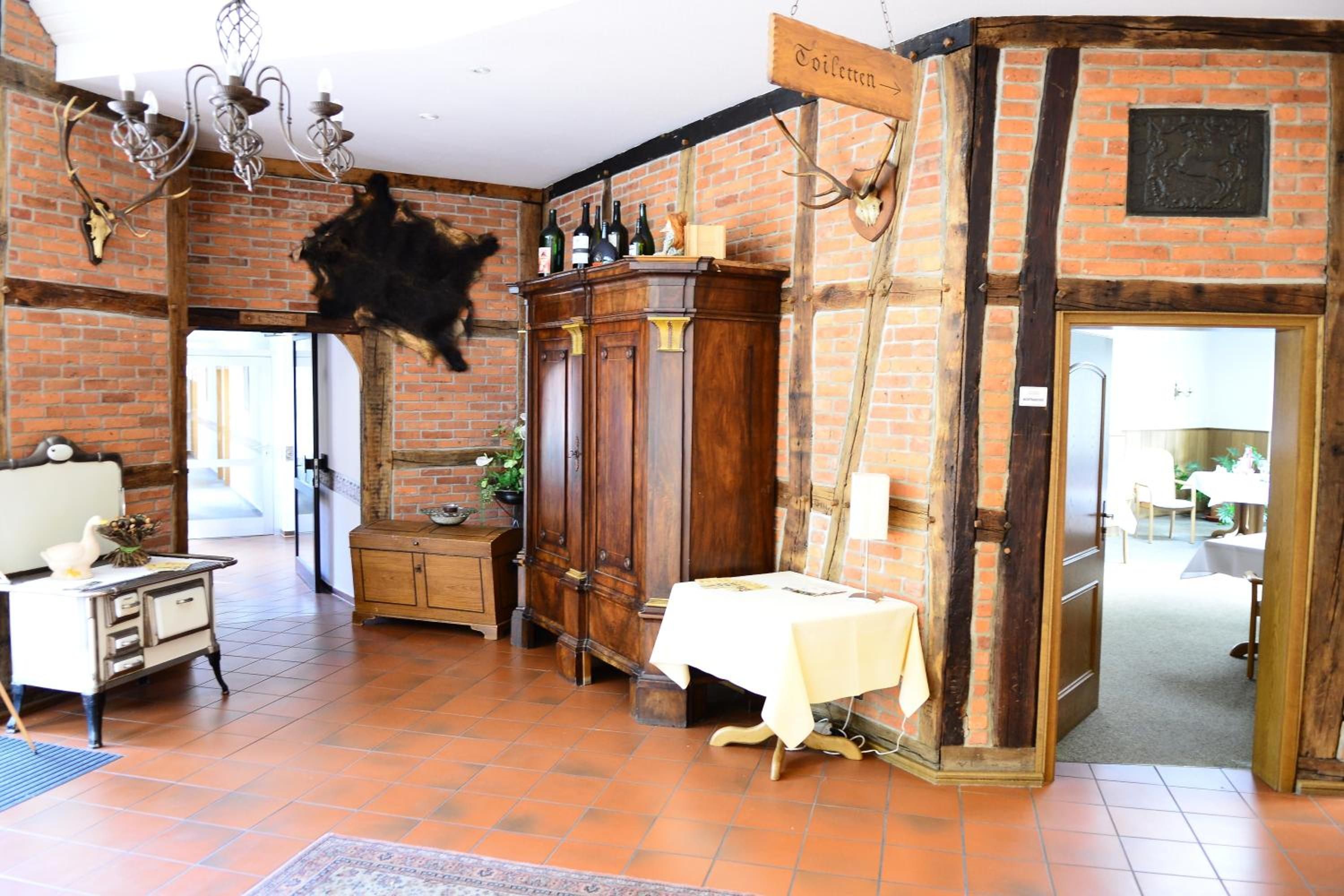 A rustic room with exposed brick walls, a wooden cabinet, a table with a white tablecloth, and a chandelier.