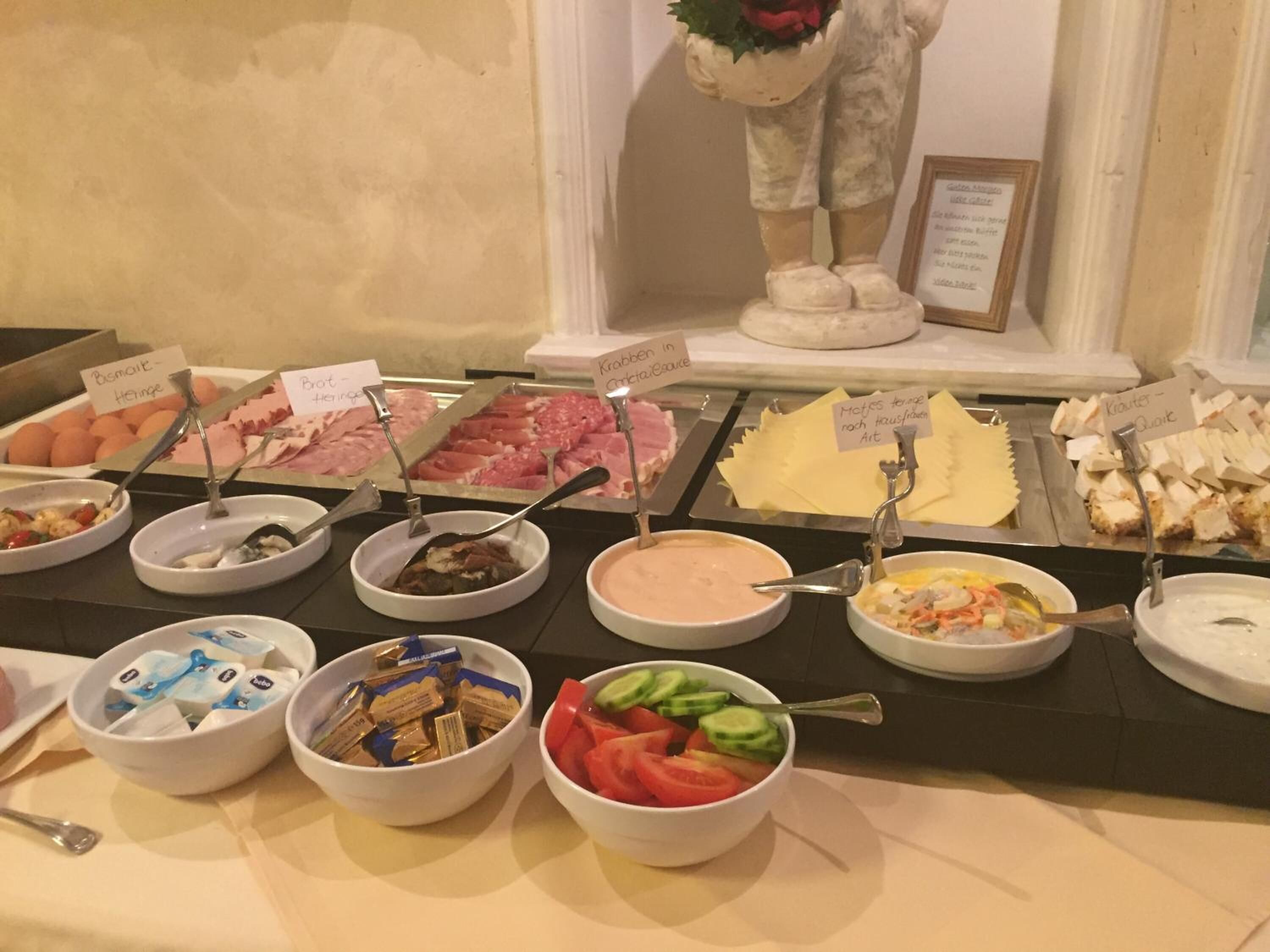 Un bufé con diversas opciones de comida, incluyendo carnes, quesos y ensaladas.