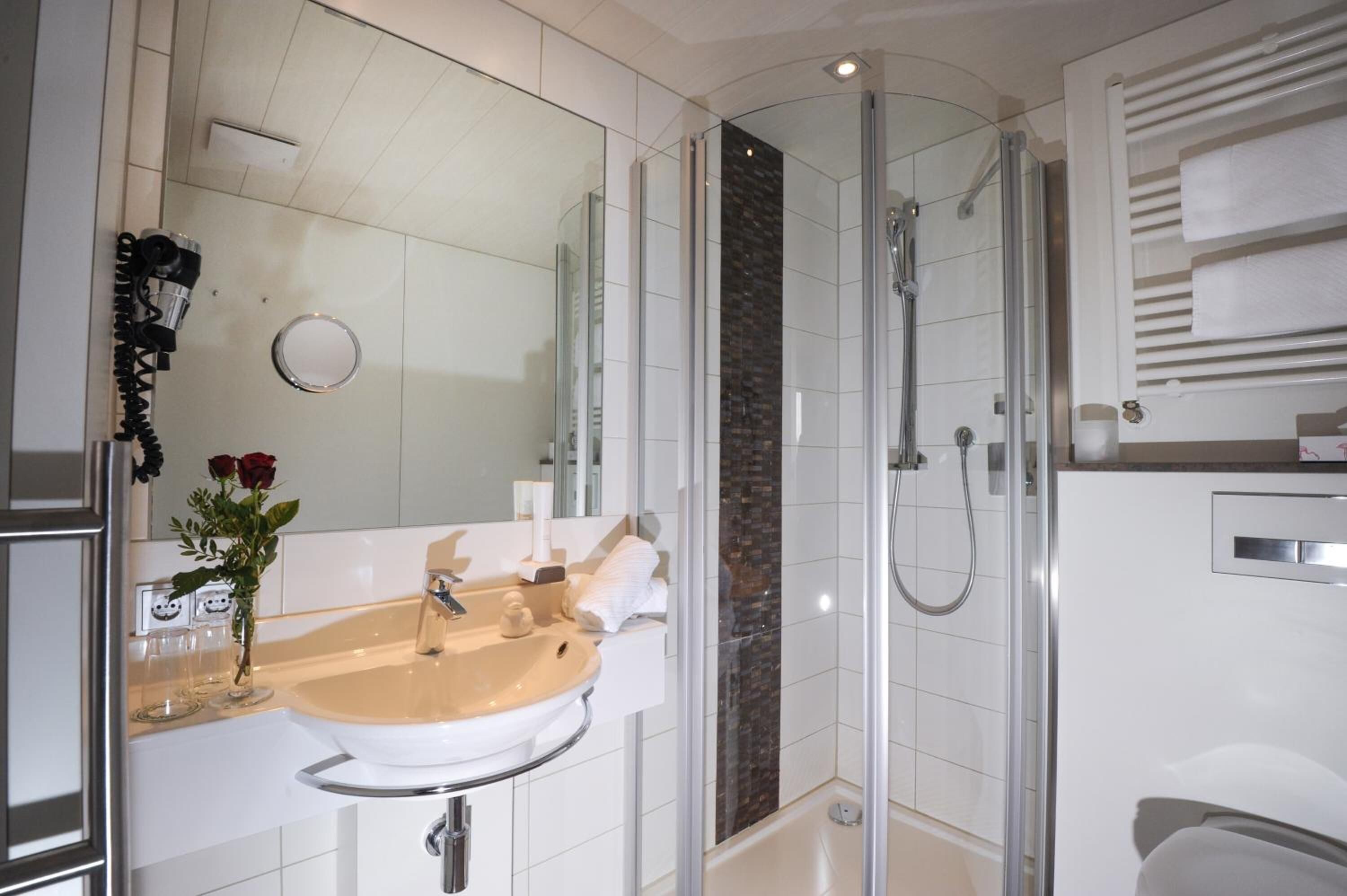 A modern bathroom with a glass-enclosed shower, a beige sink, and a mirror.