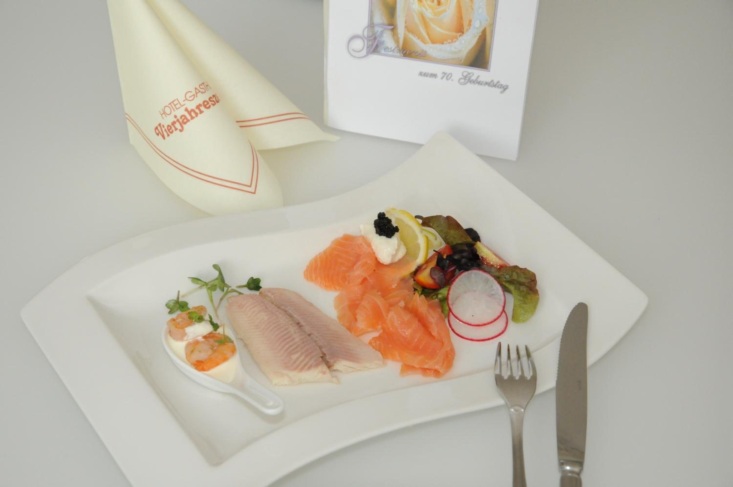 Une assiette blanche contenant divers fruits de mer, notamment du saumon et des crevettes, posée sur une nappe blanche.