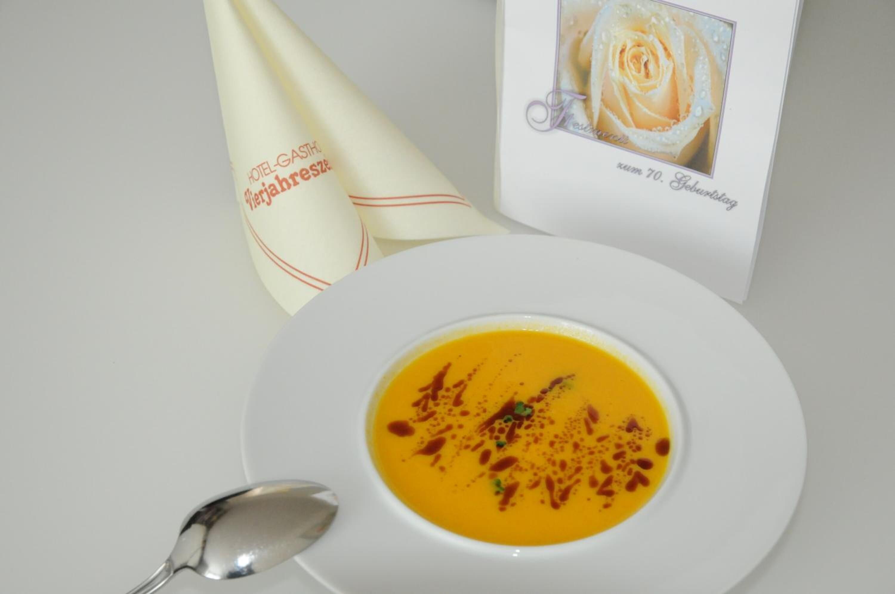 A bowl of soup with a spoon and a napkin with text, and a card with a rose and text.