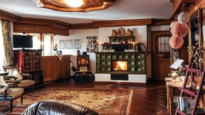 A cozy living room with a fireplace, wooden furniture, and a reception area.