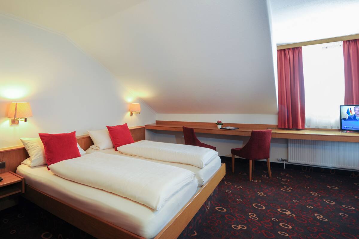 Habitación de hotel con una cama grande, dos mesitas de noche, un escritorio, una silla y un televisor.