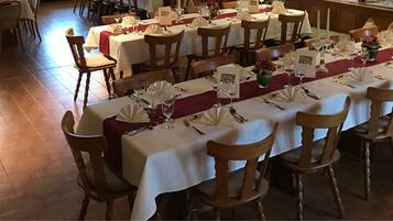 A long dining table set with white tablecloths, red runners, and neatly arranged cutlery.