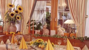 A dining table set with yellow napkins, sunflowers, and a vase of flowers.