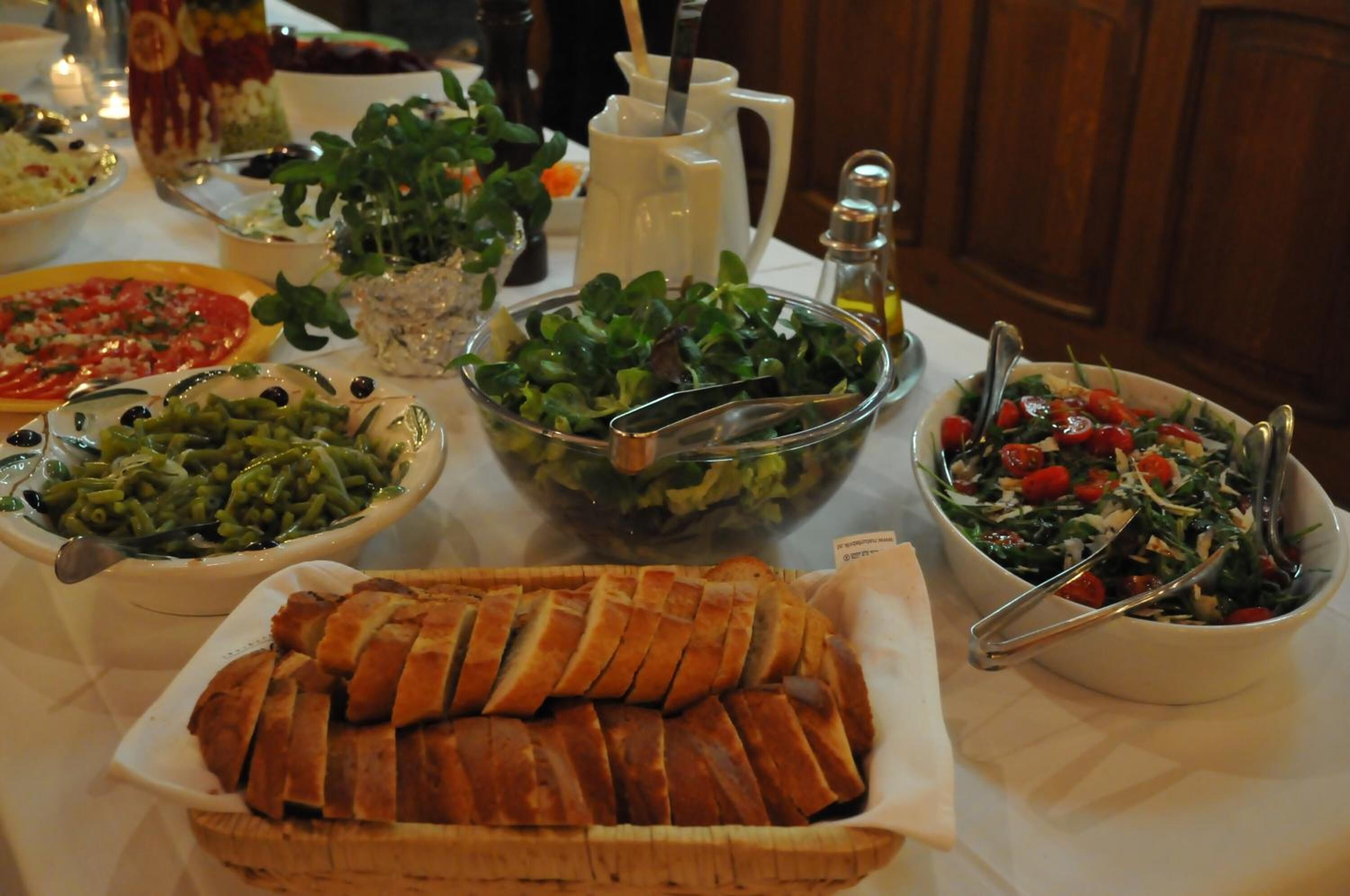 Una mesa con diferentes platos, incluyendo una ensalada, pizza y una cesta de pan.