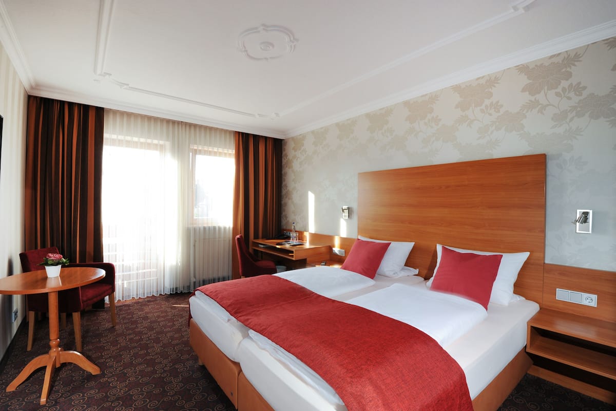 Una habitación de hotel con una cama grande, un escritorio, una silla y una mesita.