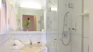 A bathroom with a glass-enclosed shower, a sink with a mirror, and a toilet.