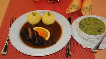 A plate of food with dumplings, a slice of lemon, and a piece of meat in broth, along with a bowl of soup.