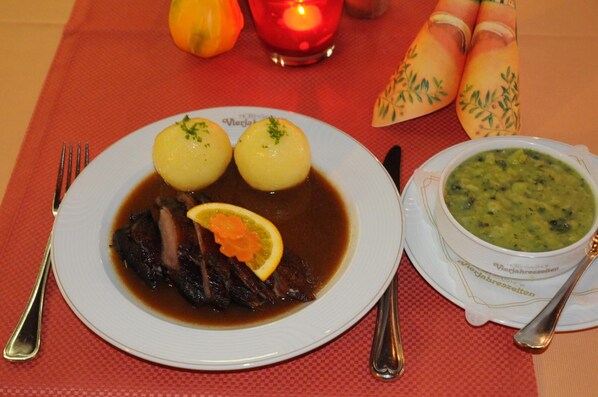 Un plato de comida con albóndigas, una rodaja de limón y un trozo de carne en caldo, junto con un tazón de sopa.